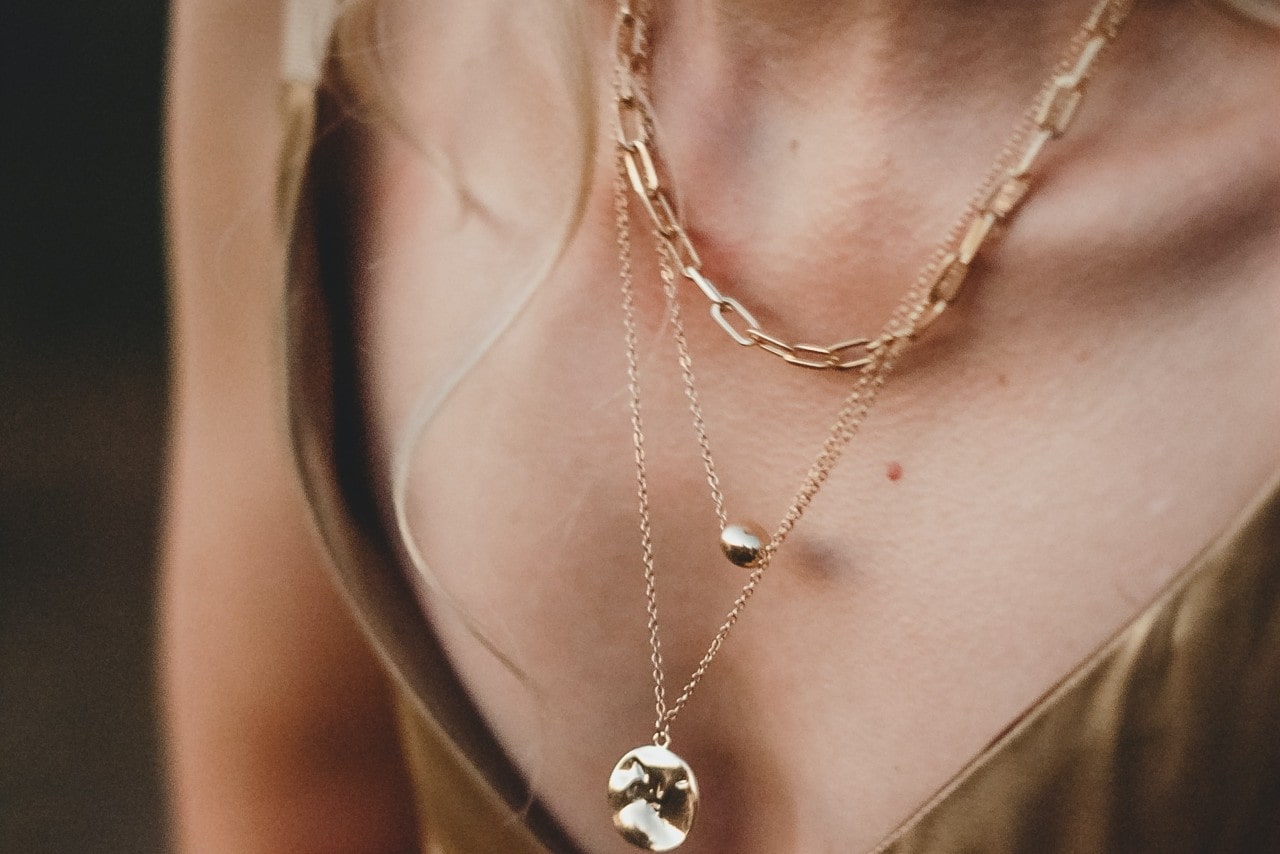 close-up image of a woman’s necklace adorned with three yellow gold necklaces