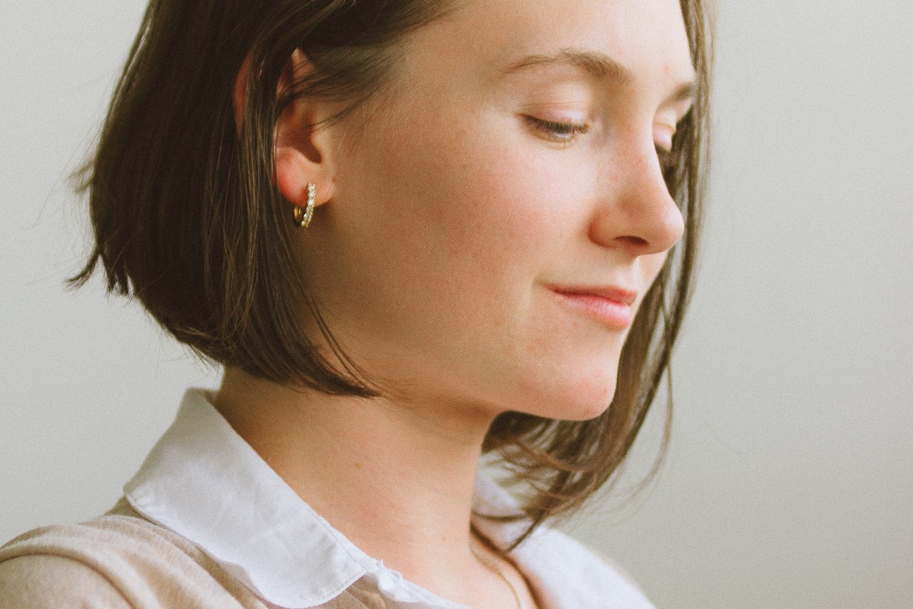 a woman facing away from the camera, wearing yellow gold huggie earrings with diamonds