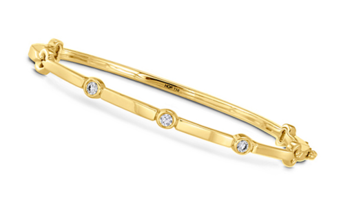 A delicate yellow gold bangle with bezel set diamonds from Hearts on Fire, available at Chrono Jewelry.