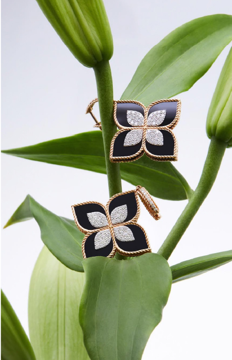 A black and yellow gold earrings on a green leaves