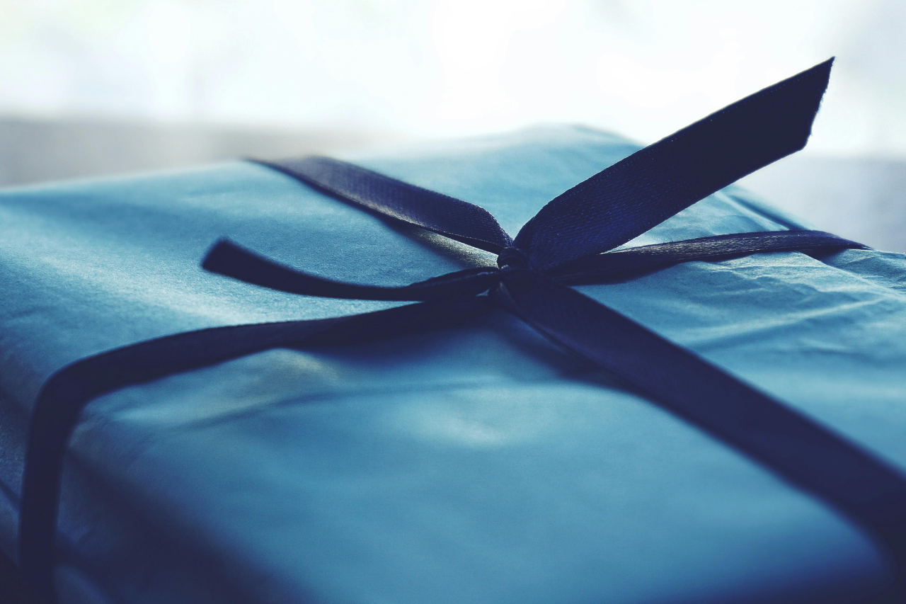 A close-up of a simple blue gift box tied with a dark blue ribbon.