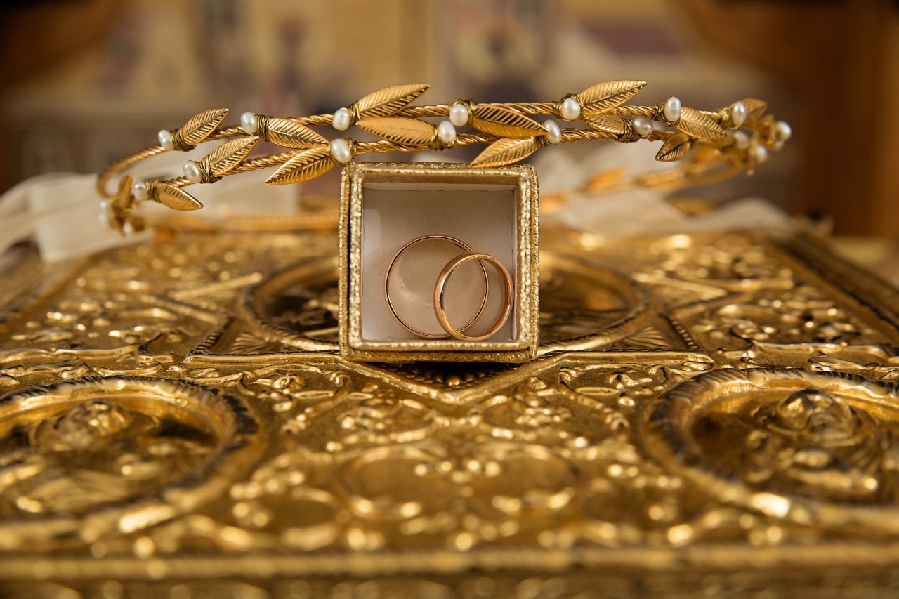 Gold rings inside a golden box with a gold and pearl bracelet resting on top.