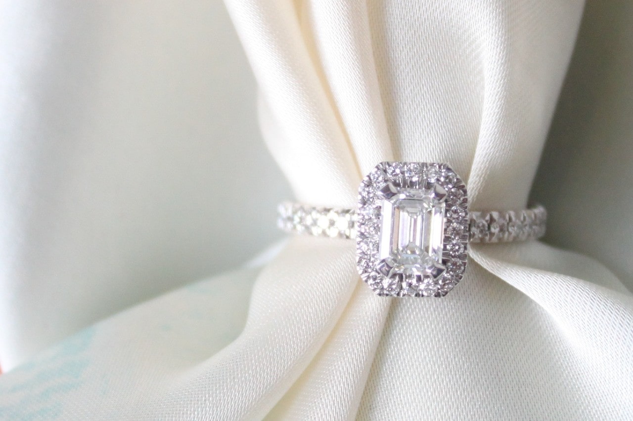 a halo engagement ring with a piece of white fabric threaded through it