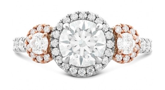 A white gold and rose gold three stone engagement ring by Hearts On Fire with halos around each stone and along the band