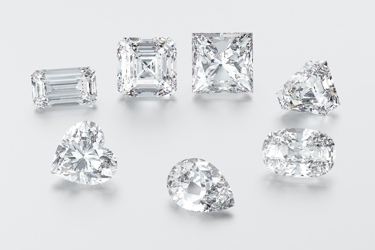 A group of diamonds, featuring different diamond shapes, sit on a white backdrop.