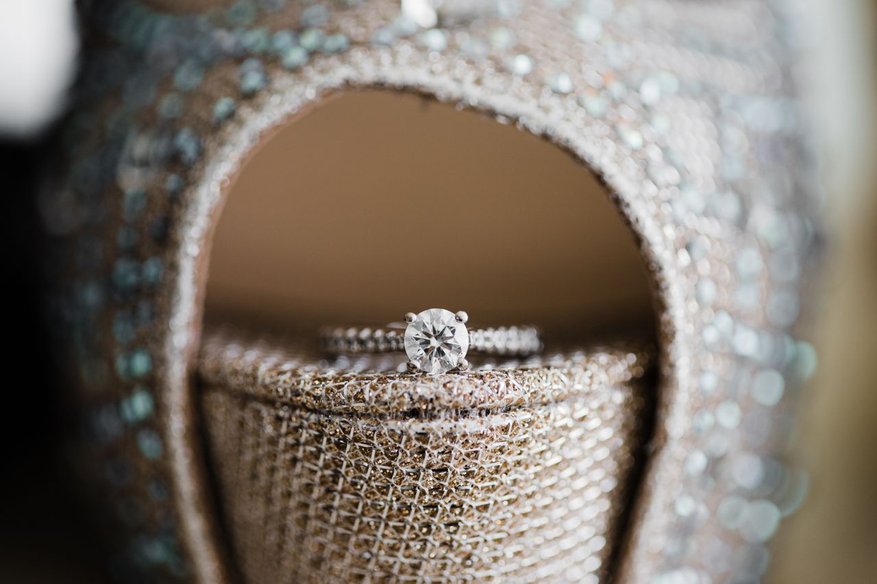 A round cut engagement ring sits on the toe of a champagne heel.