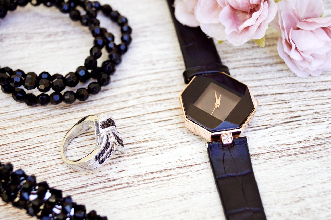 an avant-garde shape watch case on a table next to other jewelry