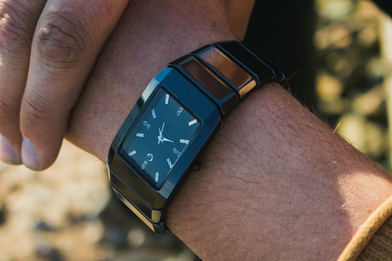 a man’s wrist wearing a rectangular case watch