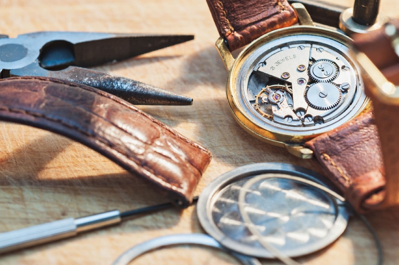 An open watch case being cleaned and prepared for watch winding.