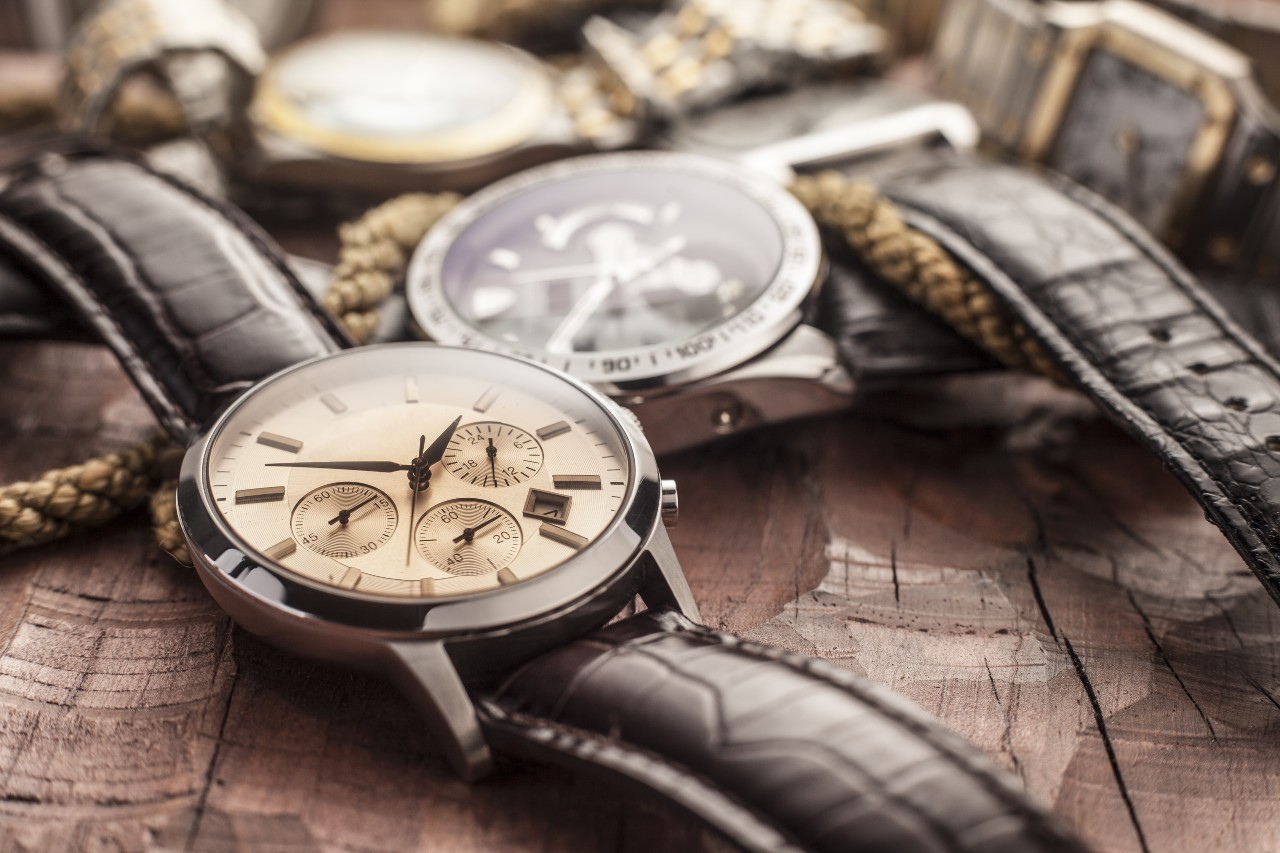 A collection of watches messily strown on a wooden surface.