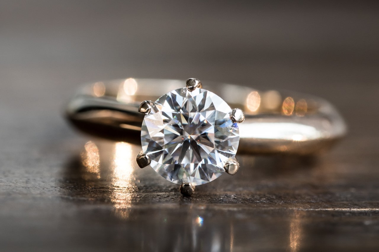 a solitaire engagement ring on a wooden table