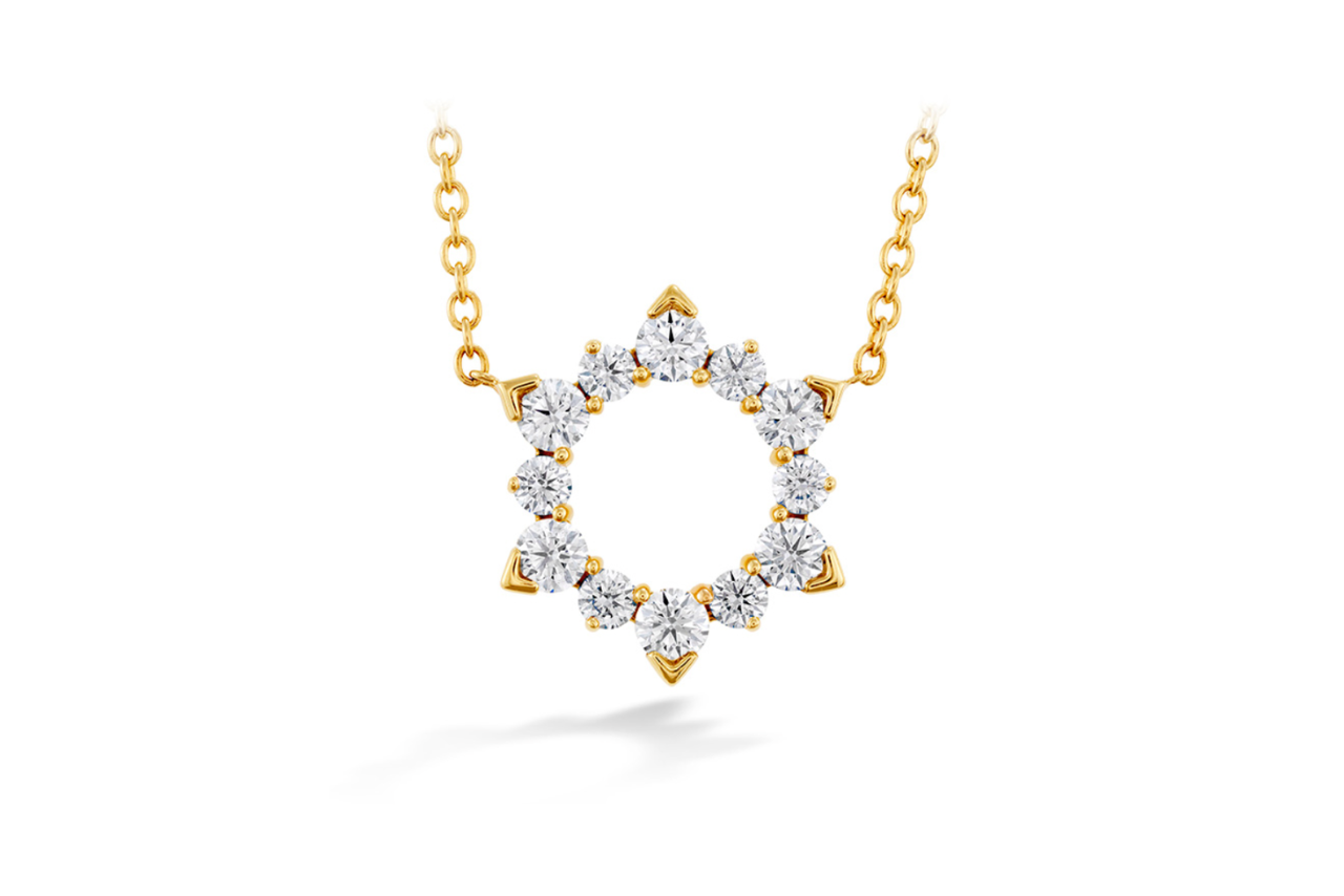 A gold pendant necklace in the shape of a sun with diamond accents.