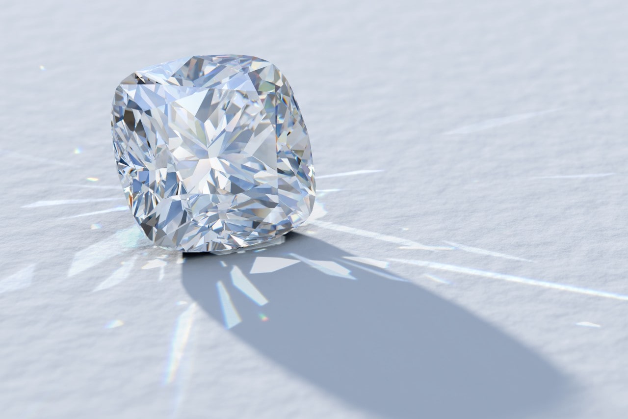 A sparkling cushion-cut diamond rests on a white surface, casting reflections around it.
